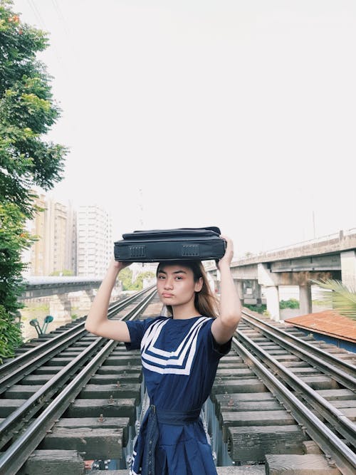 бесплатная Женщина, несущая сумку на голове, стоя на железной дороге Стоковое фото