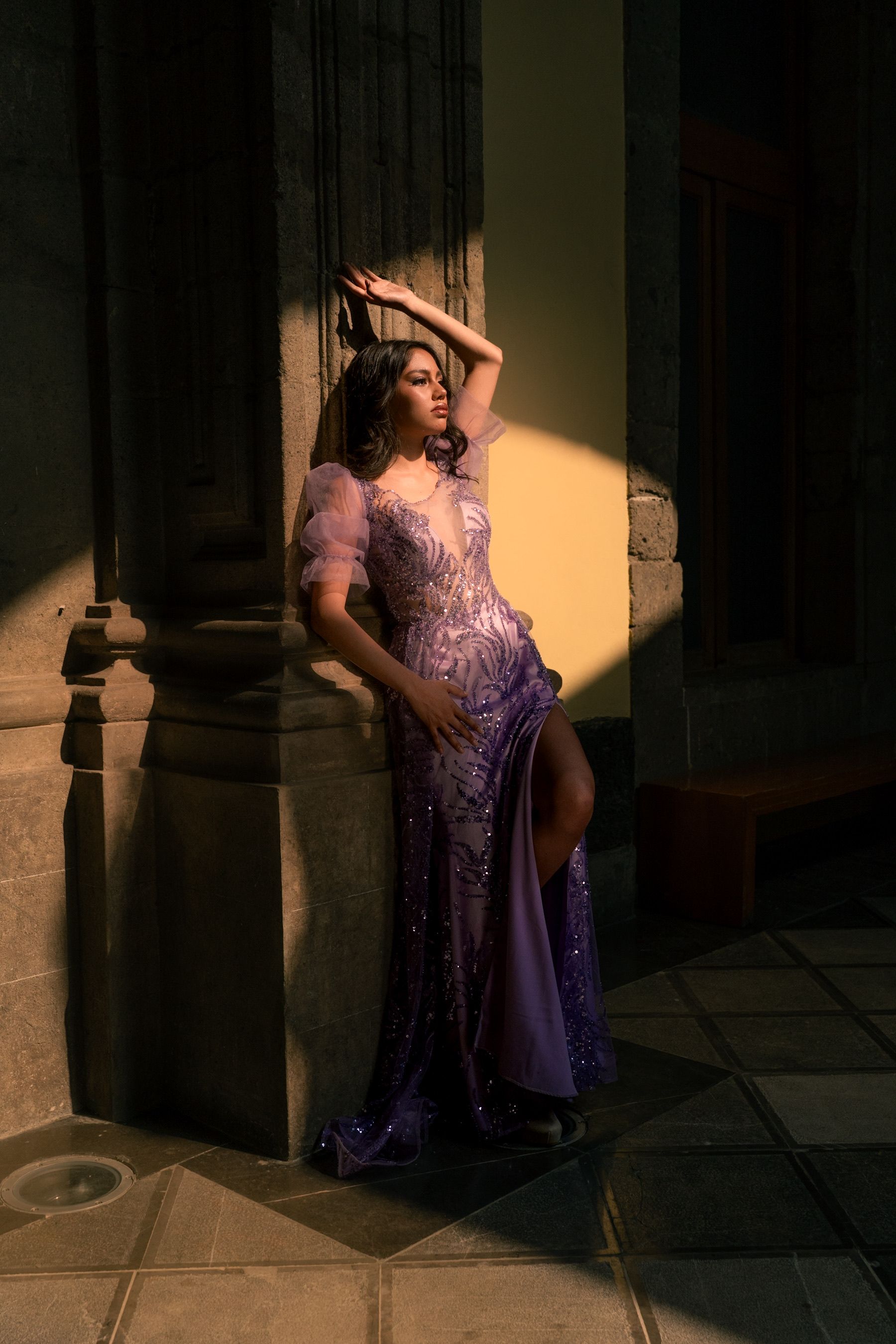 Modelo em um deslumbrante vestido roxo em pé sob sombra e luz artísticas.