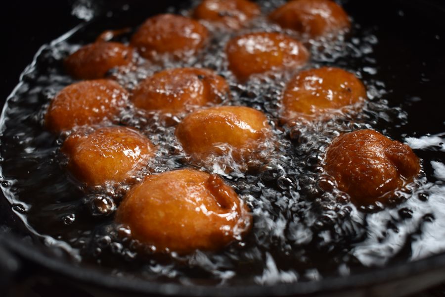 Close-up of Indian sweets frying in oil, showcasing rich textures and vibrant colors.