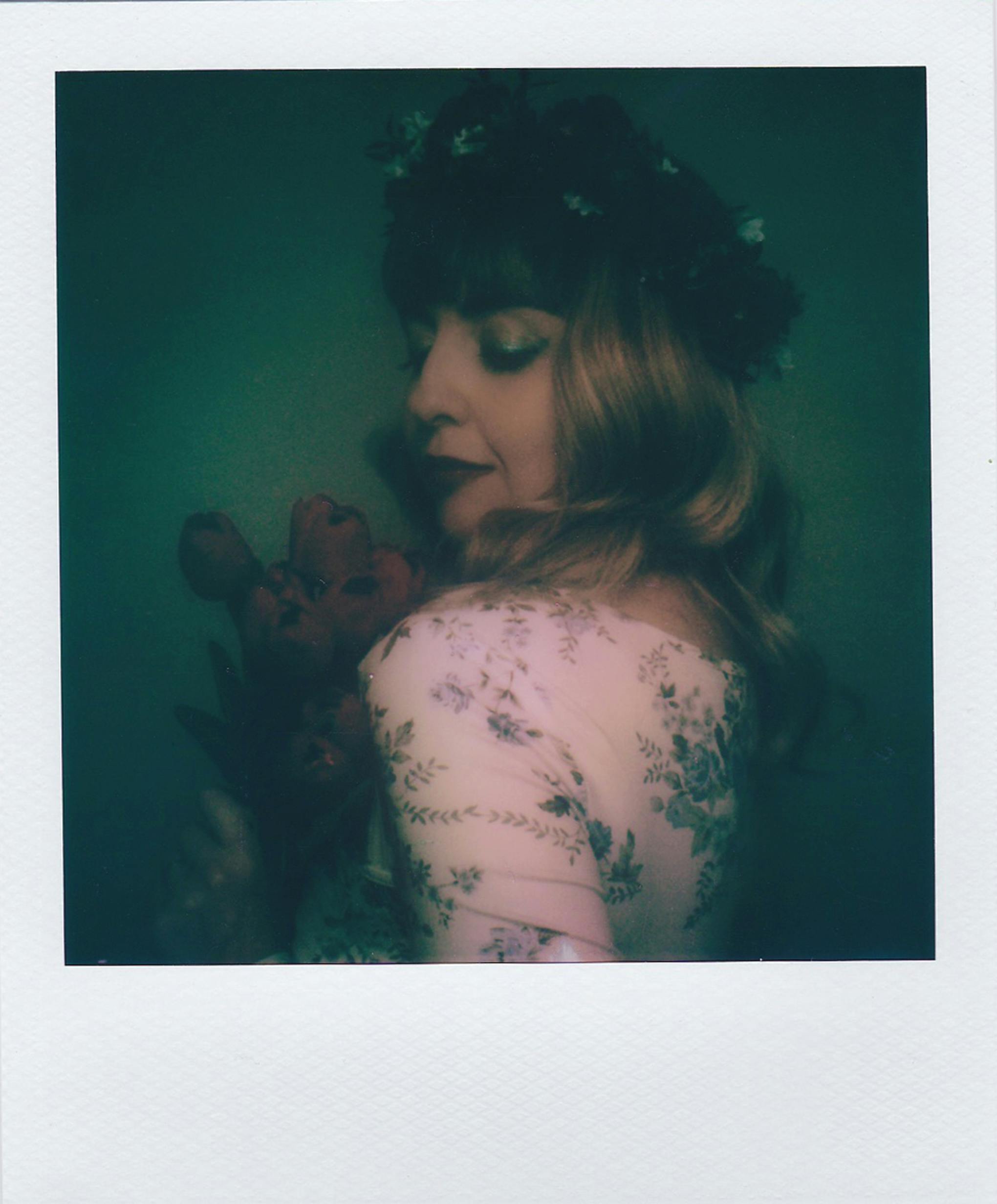 Artistic vintage portrait of a woman with floral headgear and flowers, evoking a nostalgic mood.