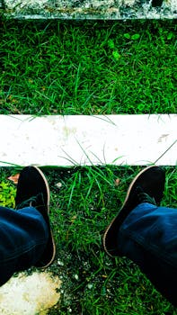 Close-up of black shoes on vibrant green grass in an outdoor setting.