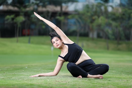 Woman practicing yoga outdoors on a green lawn performing a side stretch.