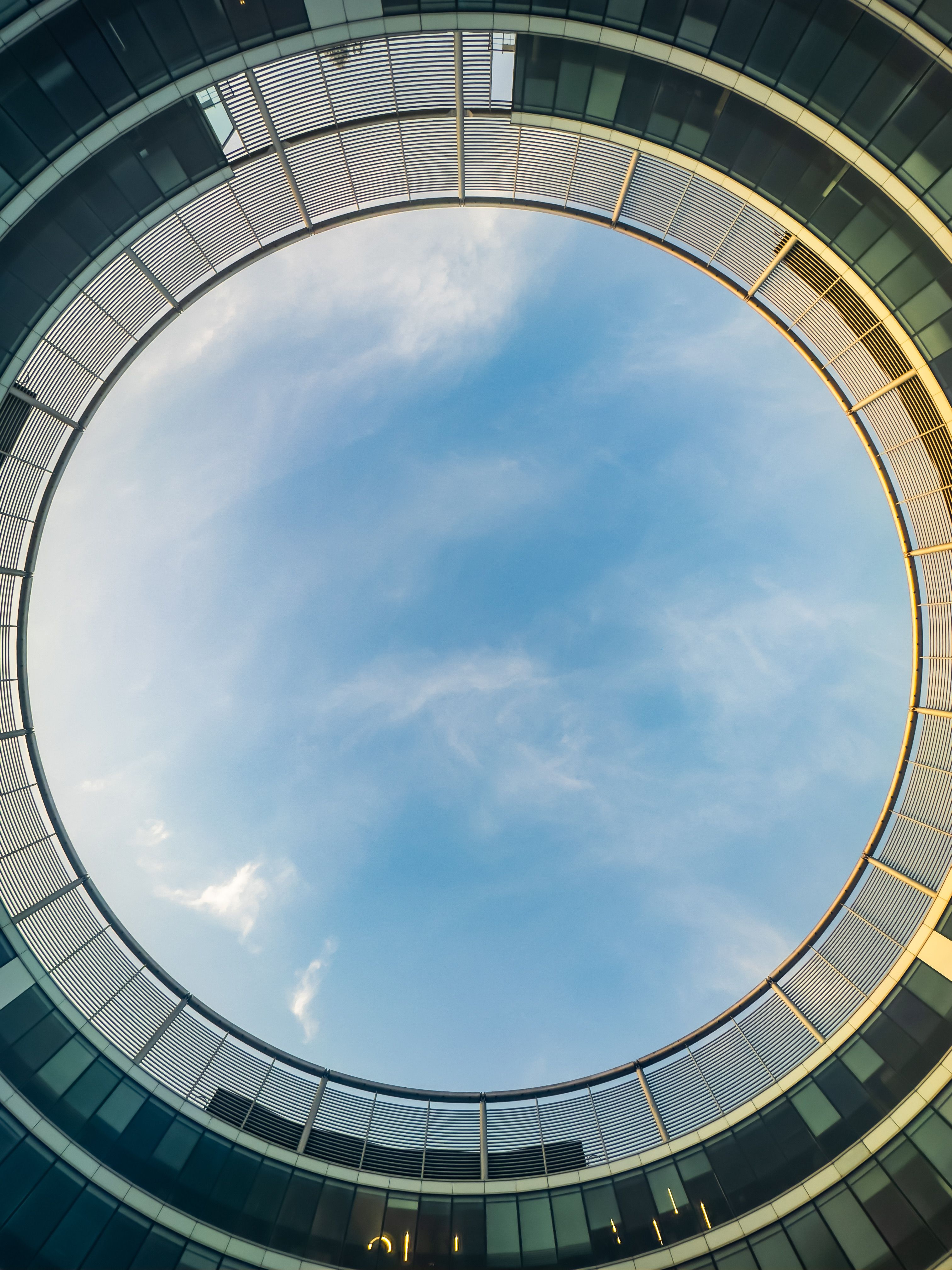 Circular view of the sky through a modern architectural structure with glass facade.