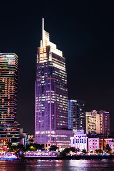 Illuminated skyscrapers in Hồ Chí Minh City reflecting on Saigon River at night.