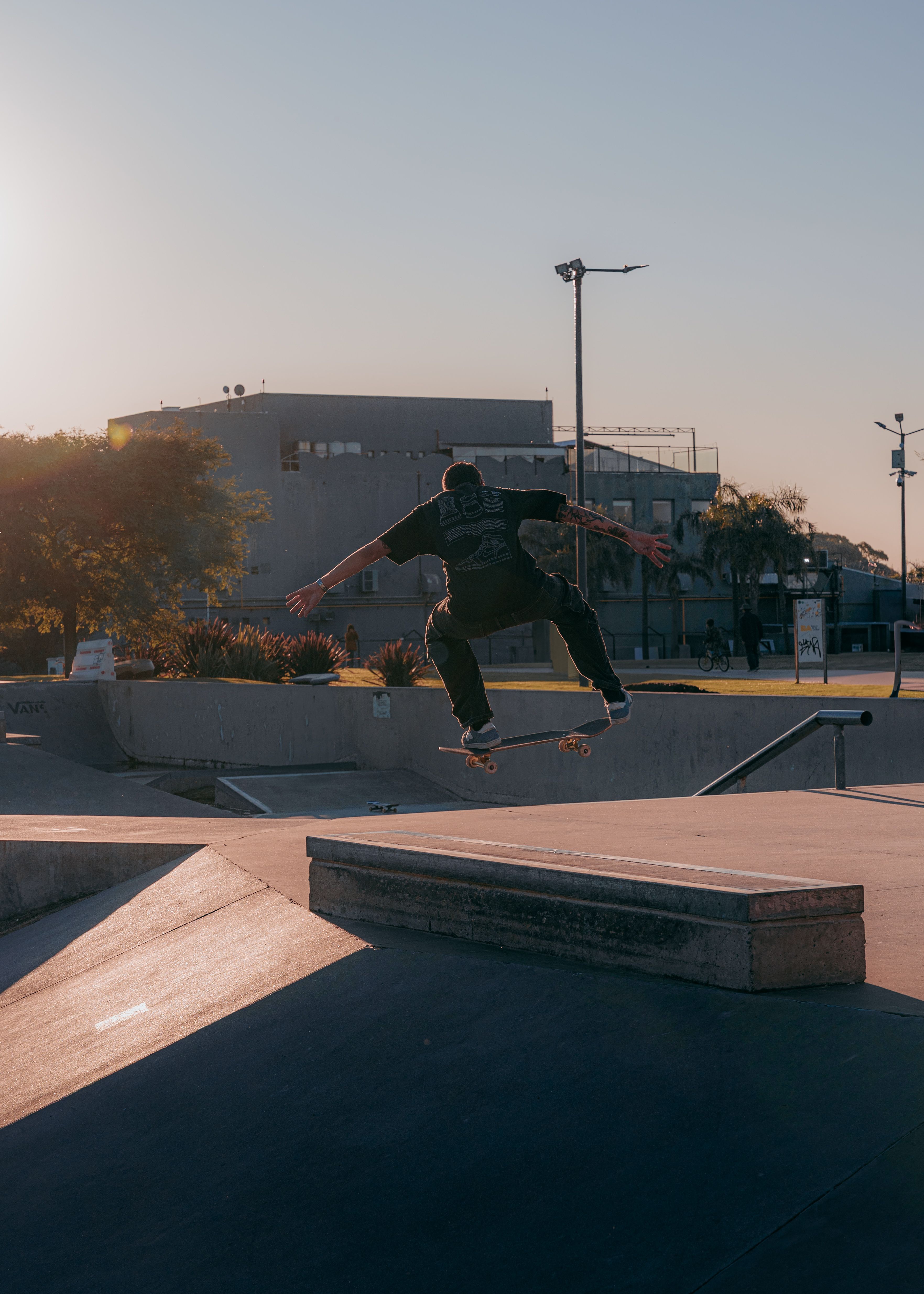 Skateboarder in mid-air performing a trick at a skatepark during daylight.. skateboarder, performing, trick
