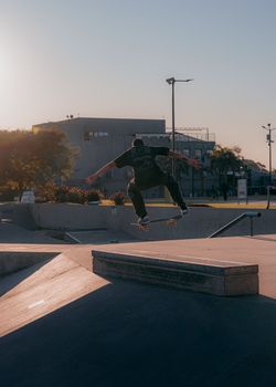 Skateboarder in mid-air performing a trick at a skatepark during daylight.. skateboarder, performing, trick