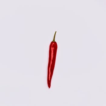 A single red chili pepper isolated on a clean white background.