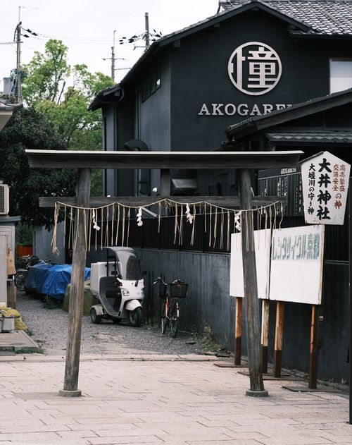 Free A serene torii gate in front of a Japanese building, symbolizing tranquility. Stock Photo