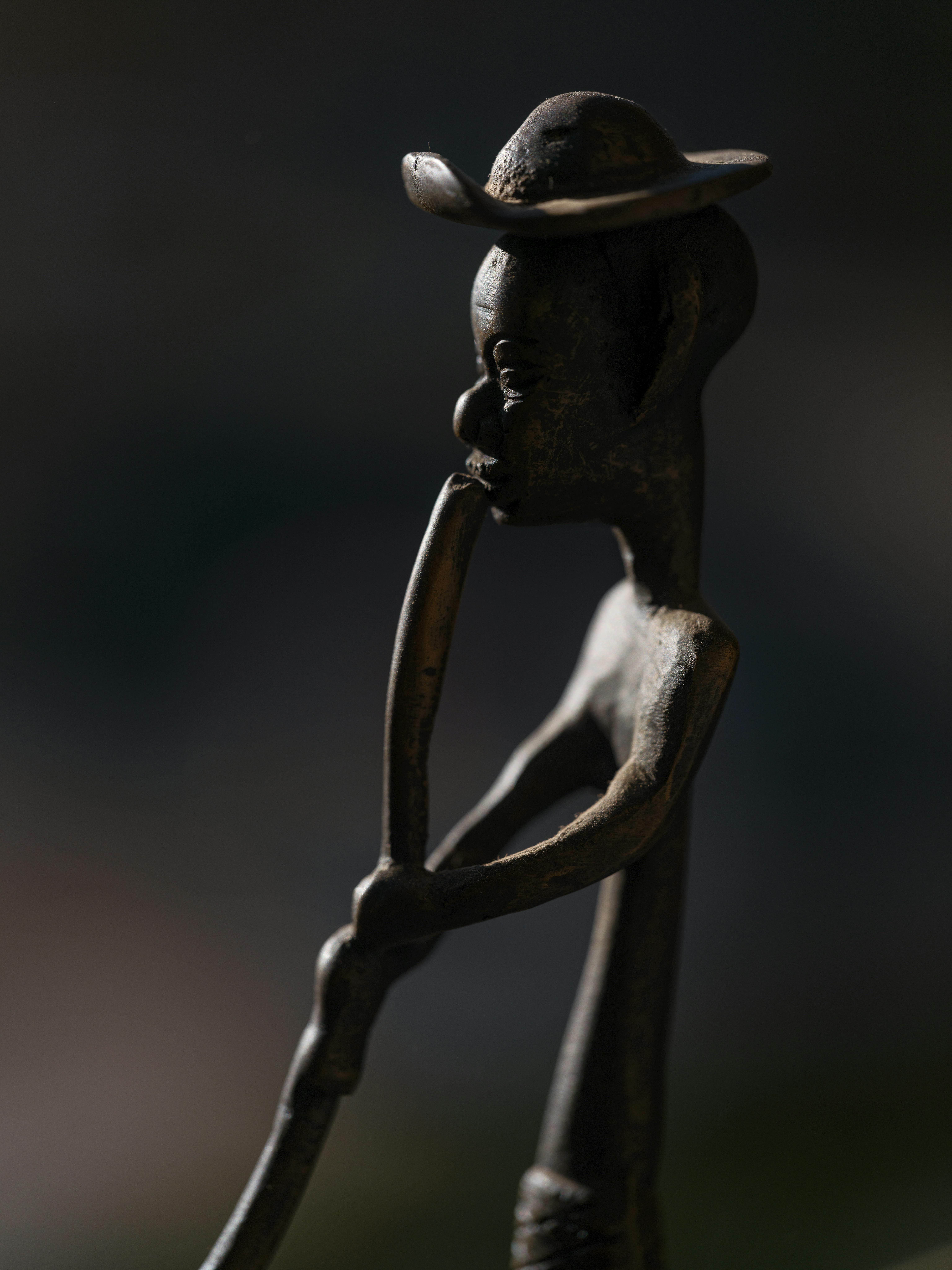 gratis Artistiek bronzen beeld van een Afrikaanse figuur die op een trompet speelt, met achtergrondverlichting. Stockfoto