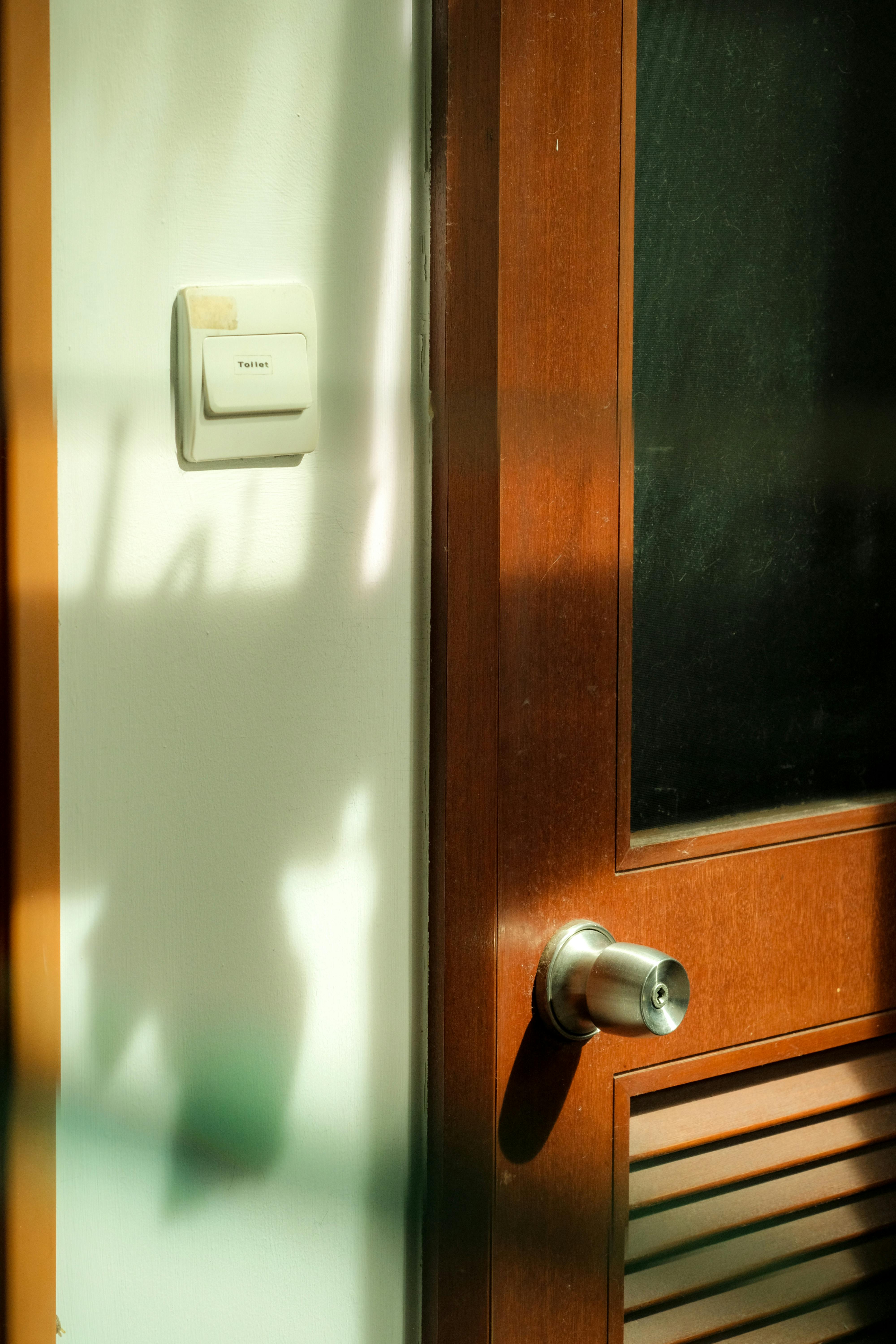 бесплатная Теплый солнечный свет отбрасывает тени на деревянную дверь и стену, создавая уютную атмосферу. Стоковое фото