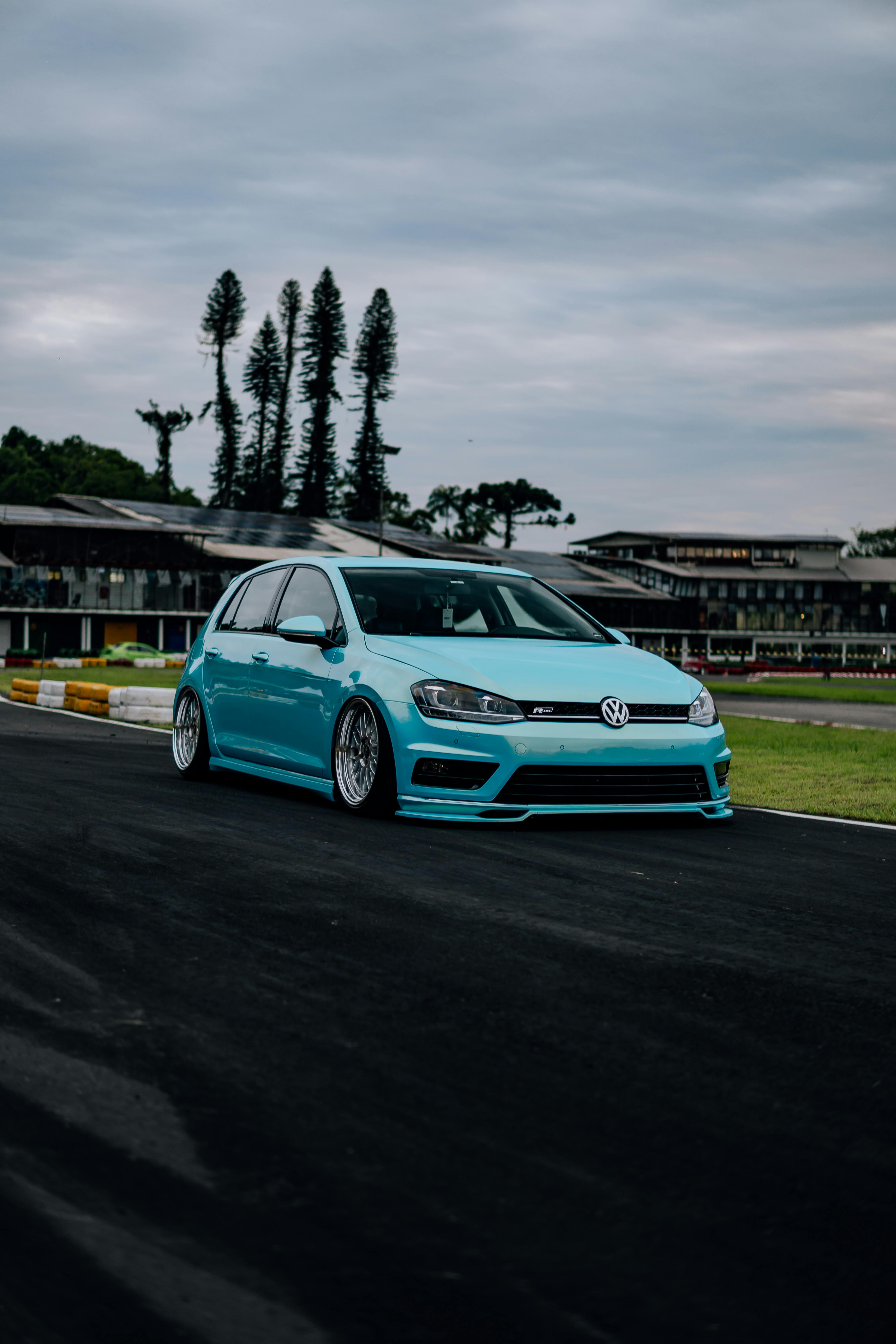 Striking blue Volkswagen Golf parked at a car meet in Brazil with a dramatic sky backdrop.