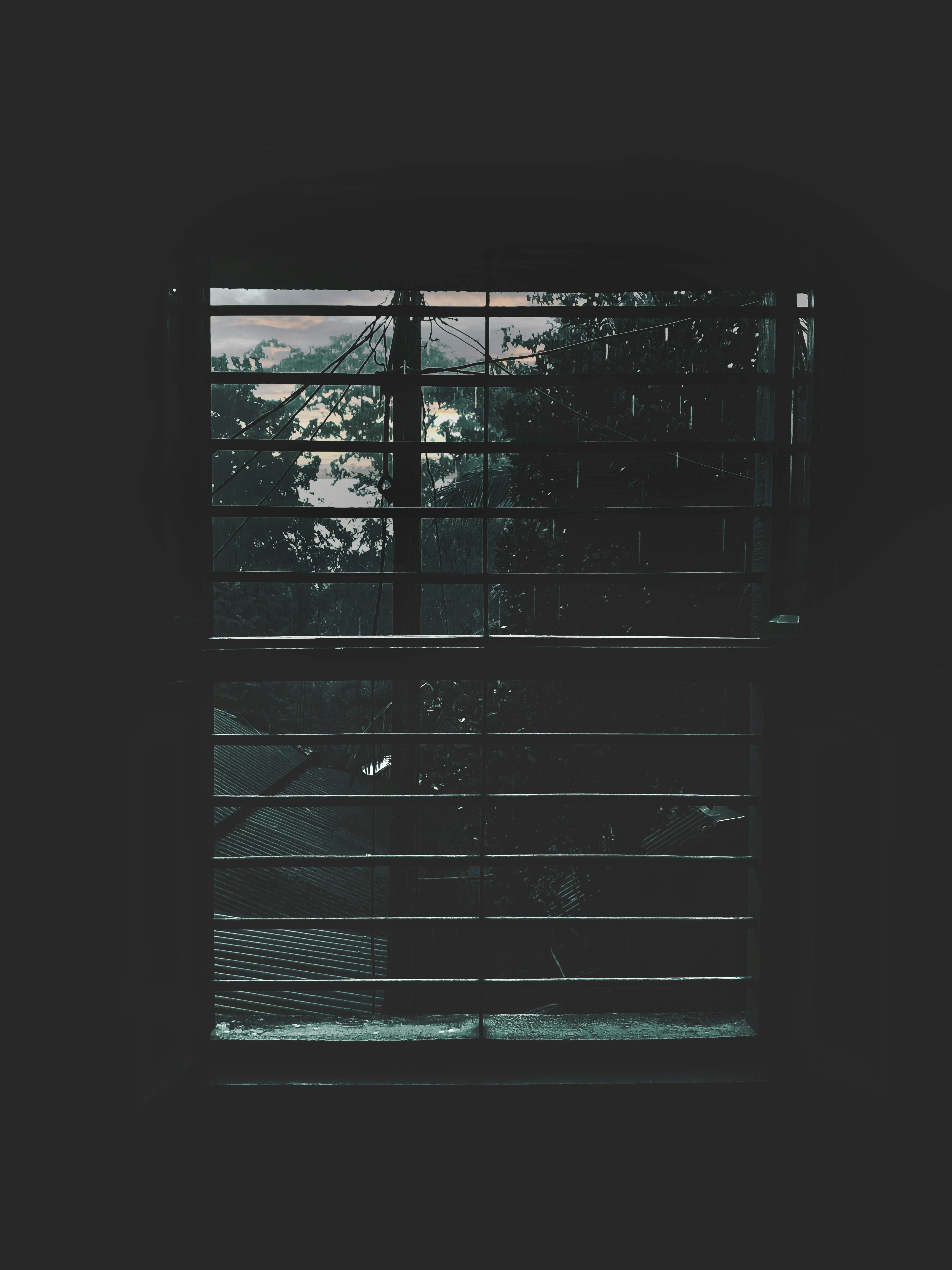 Atmospheric view of rainy weather through window blinds, evoking a moody ambiance.