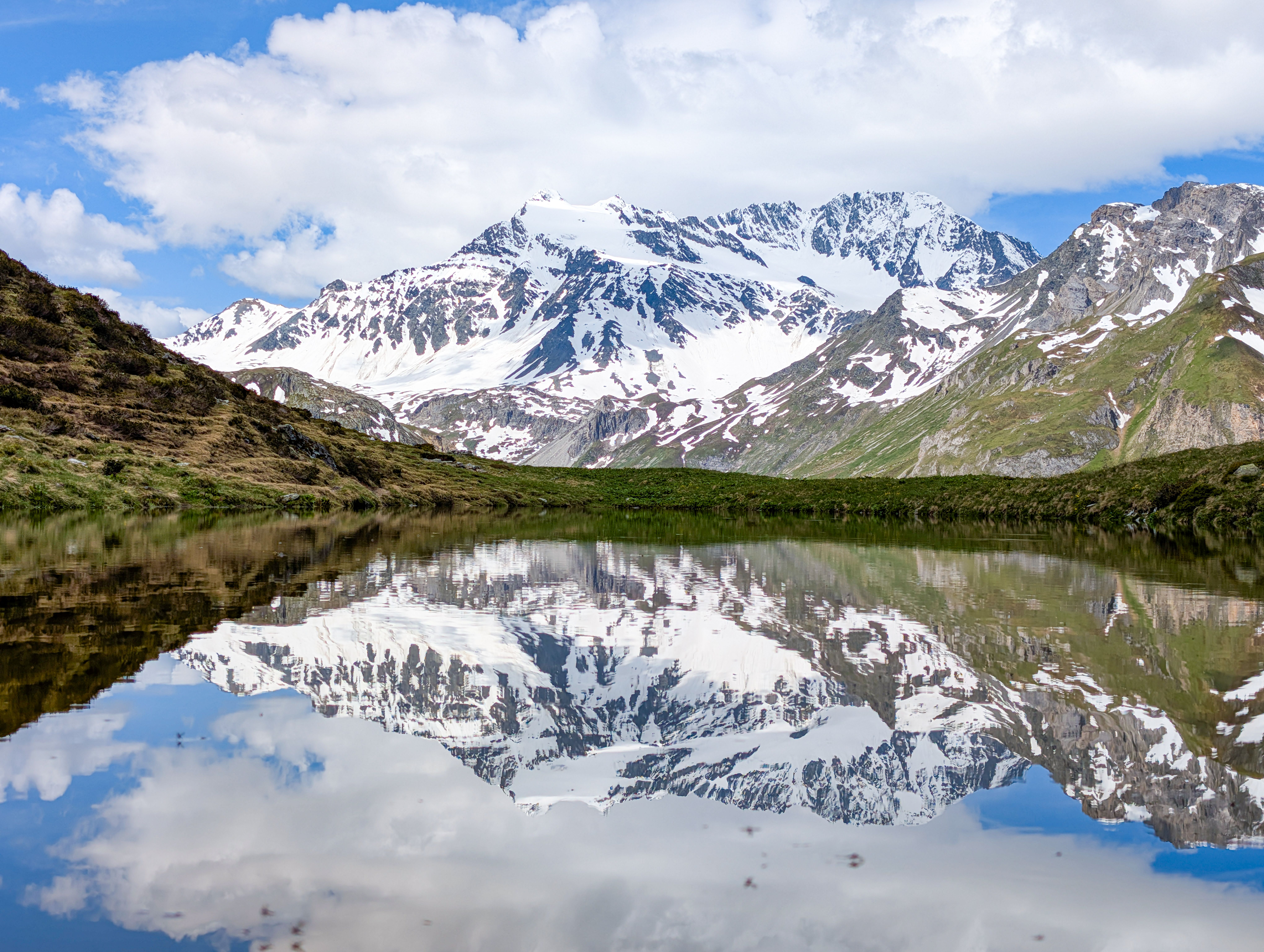 Explore the serene reflection of the snow-capped Vanoise Mountains in a tranquil lake in Pralognan-la-Vanoise, France. - Parque natural de Vanoise