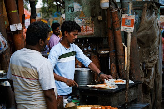 Street vendor skillfully prepares Indian dish at vibrant outdoor market. Authentic cooking scene.