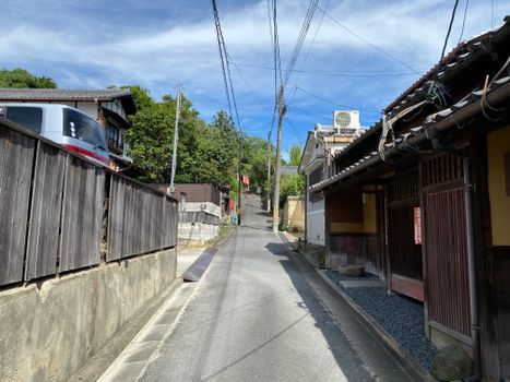 Charming narrow street in Arashiyama, Kyoto, lined with traditional houses, captured under a clear blue sky.