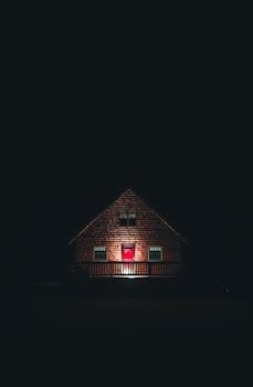 A captivating wooden house with a red door, illuminated at night in a moody setting. Perfect for architectural and real estate themes.