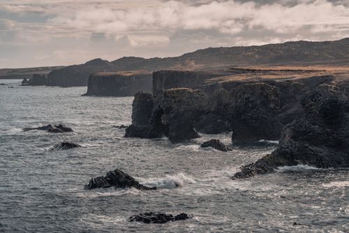 Free Powerful waves crash against volcanic cliffs in Iceland, capturing the rugged beauty of the landscape. Stock Photo