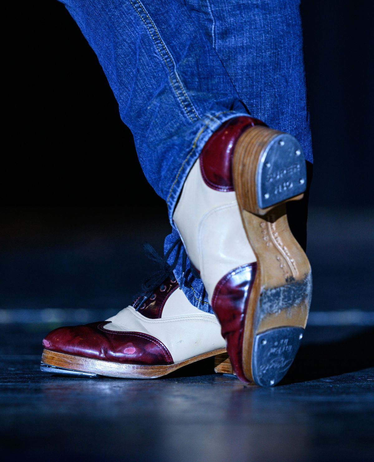 Tap shoes moving under warm stage lights