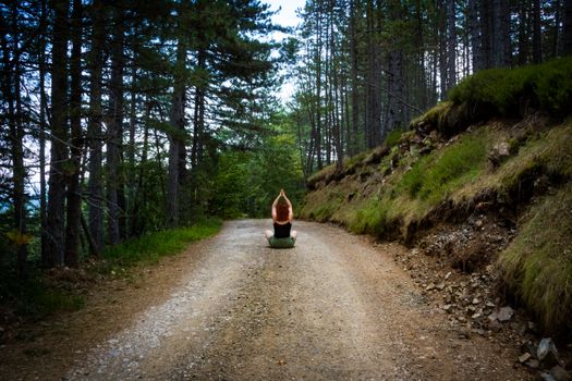 Yaz mevsiminde orman yolunda meditasyon yapan, doğanın dinginliğine sarılan bir kişi.