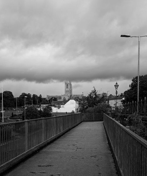 Free Black and white photo of a gothic cathedral from a bridge under a moody sky. Stock Photo