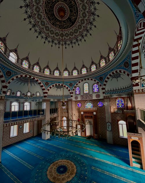 Free Interior view of a beautifully decorated mosque with intricate domed ceiling and stained glass windows. Stock Photo