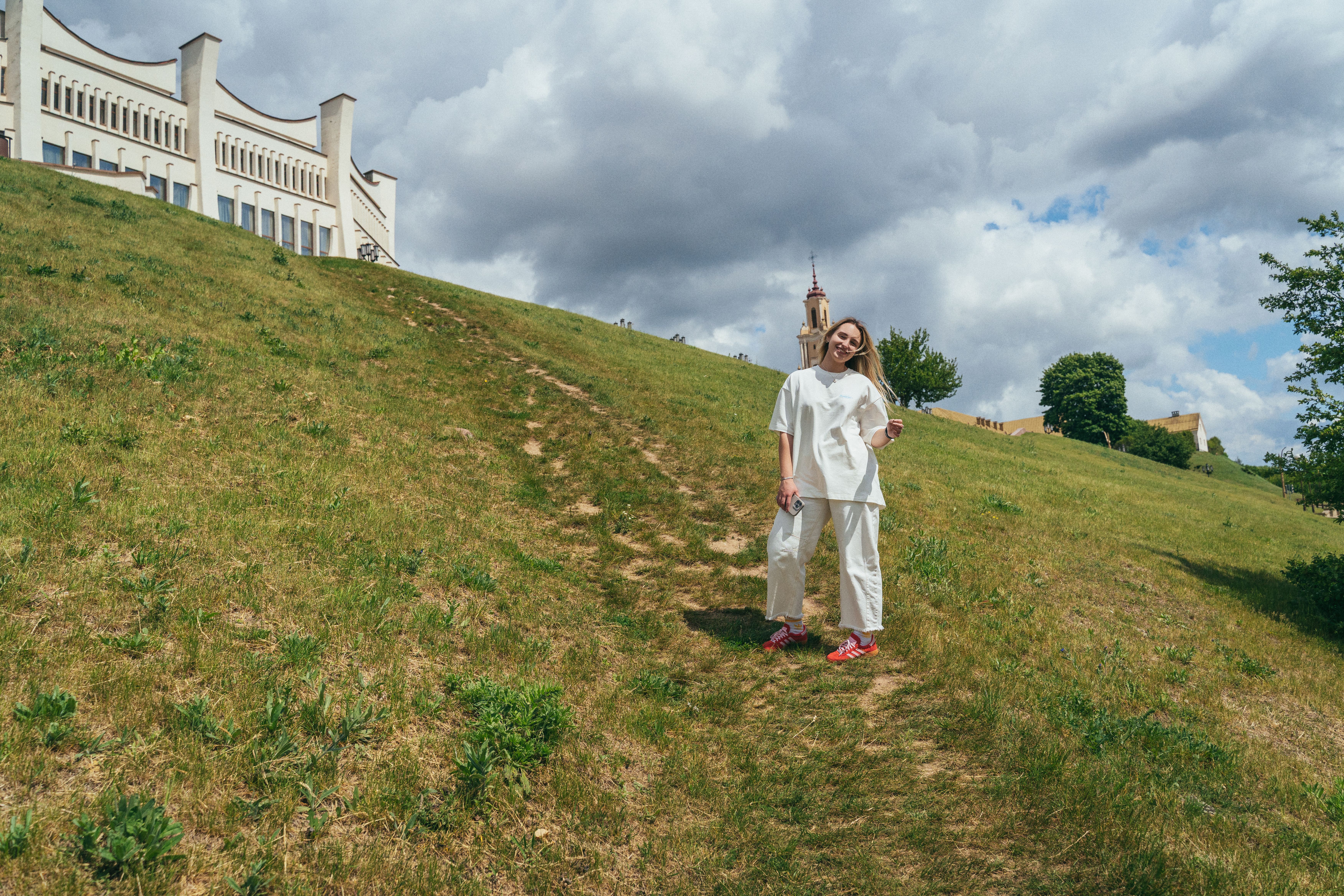Person standing on grassy hillside under cloudy sky · Free Stock Photo
