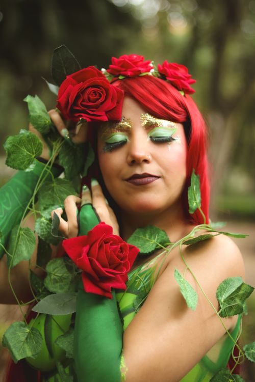 Free Woman with red roses and greenery, portraying a mythical nature figure. Stock Photo