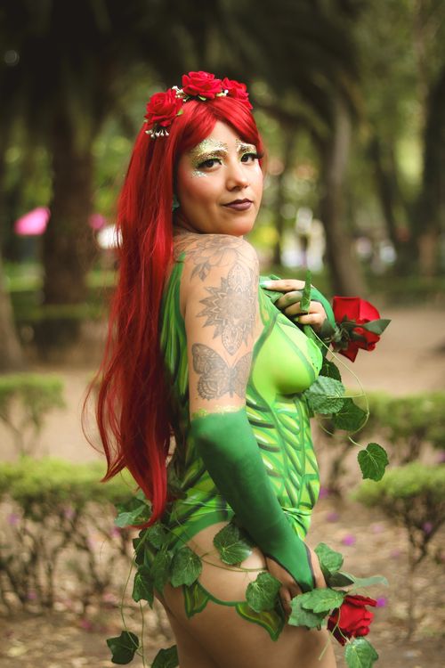Free Cosplayer in vibrant green and red costume amidst a lush park setting. Stock Photo