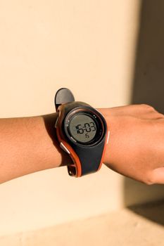 Close-up of a digital watch on a person's wrist, showcasing time in bright sunlight.