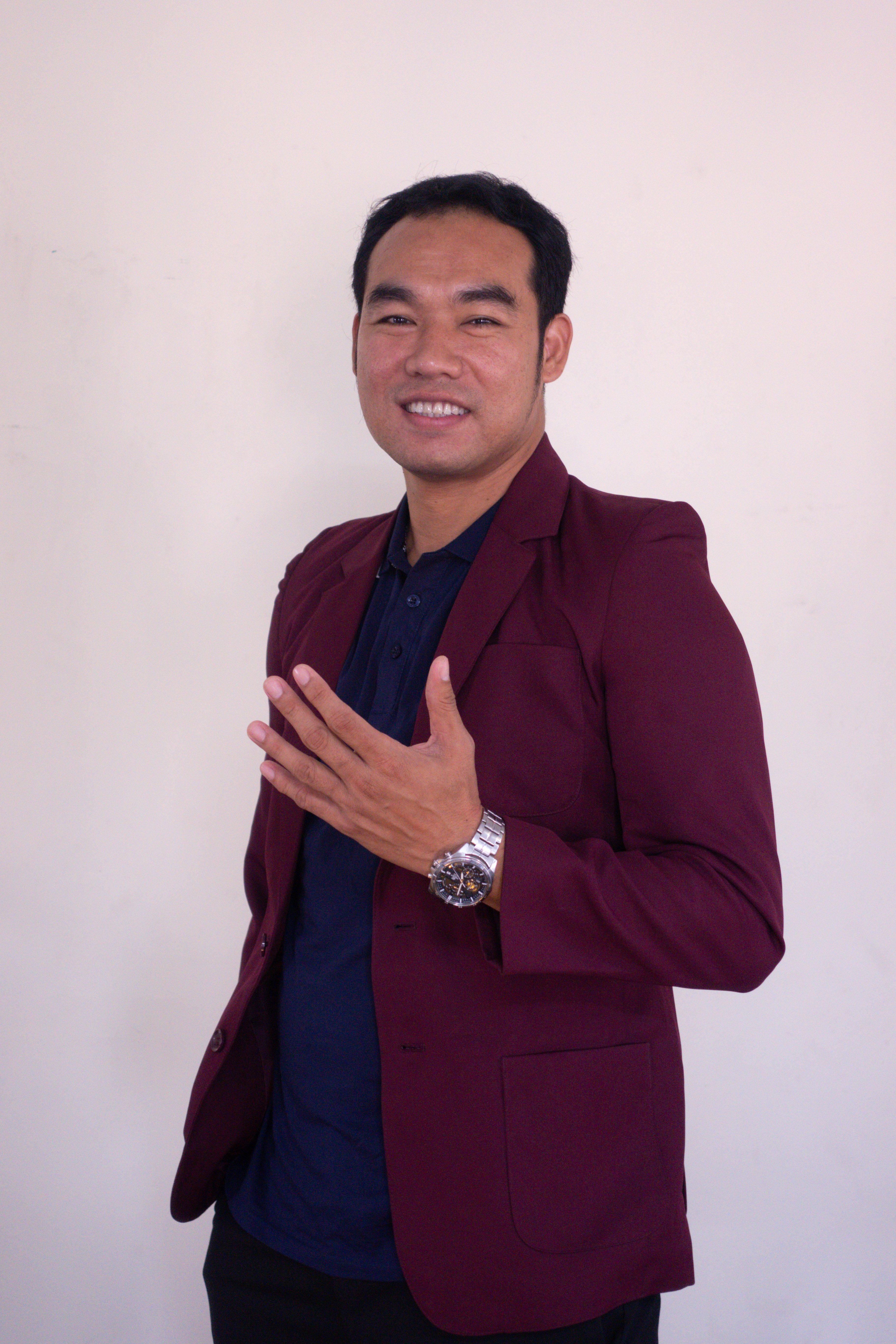 Portrait of a smiling man in a burgundy blazer, displaying confidence and style.
