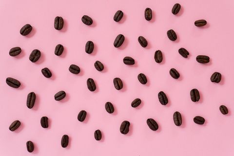 Roasted coffee beans scattered on a pink surface — photo by veronica vega on Pexels