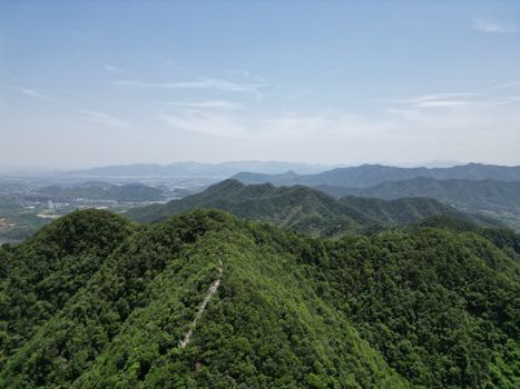 Stunning aerial view of green, forested mountains and valleys under a clear sky in China.