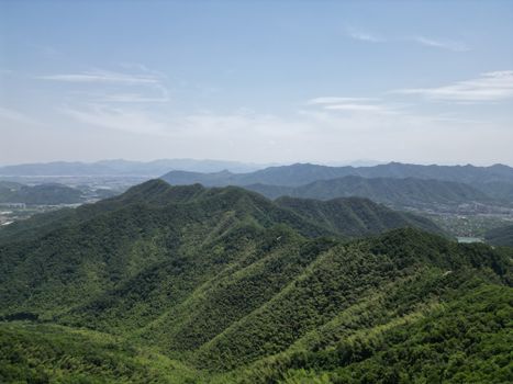 Breathtaking aerial view of lush green mountain range under a clear blue sky.