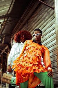 Two people in bold orange and green outfits — photo by Adefemi Adedoyin on Pexels