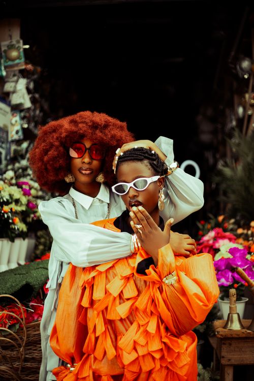 Free Two fashionable adults pose stylishly in a bustling flower market setting. Stock Photo