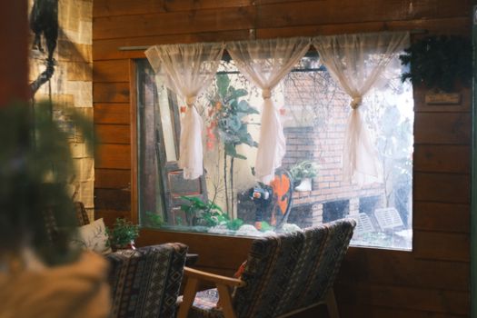 Warm rustic indoor space with chairs and a window overlooking a garden.
