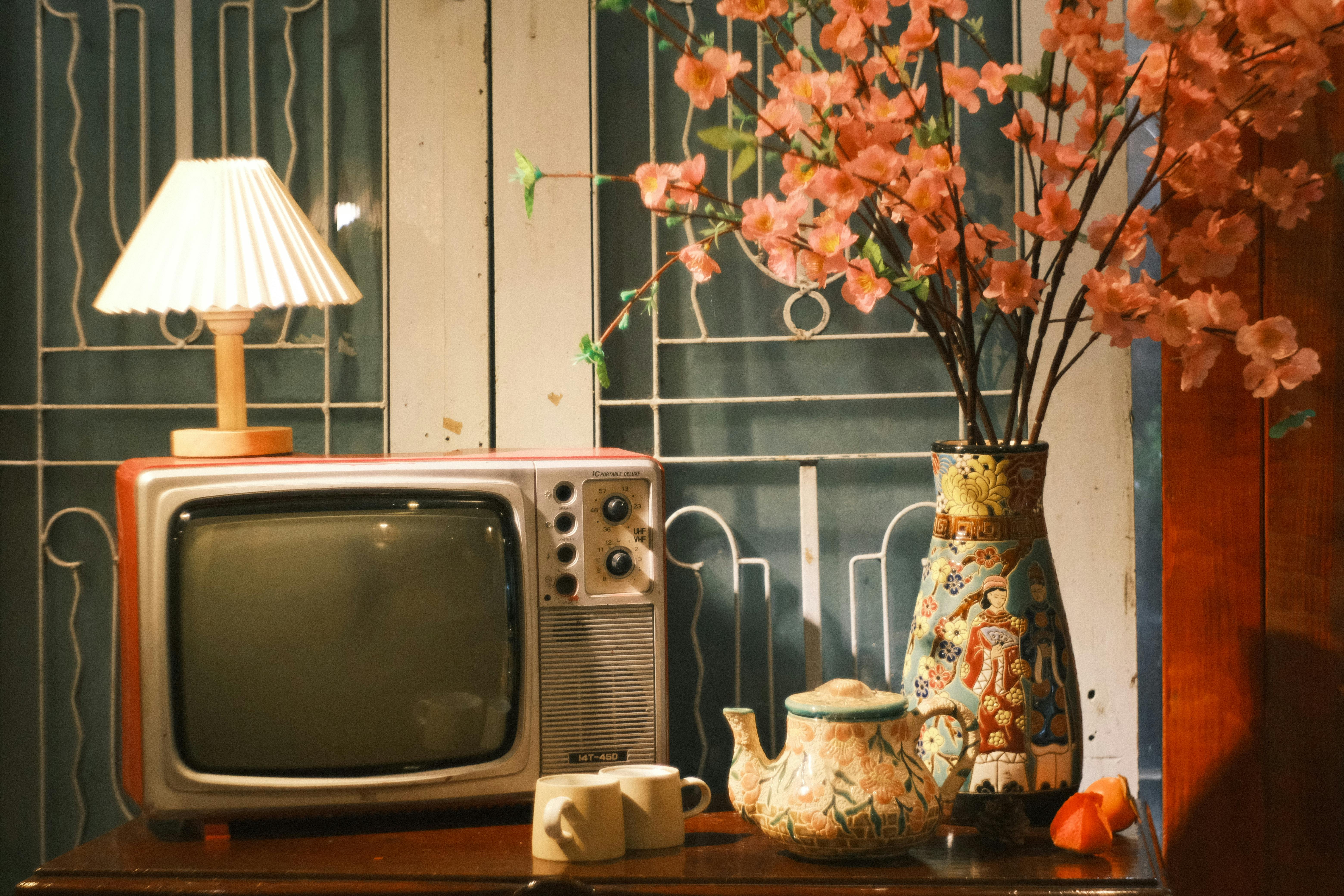 A cozy vintage scene featuring a retro TV, a lamp, and cherry blossoms.
