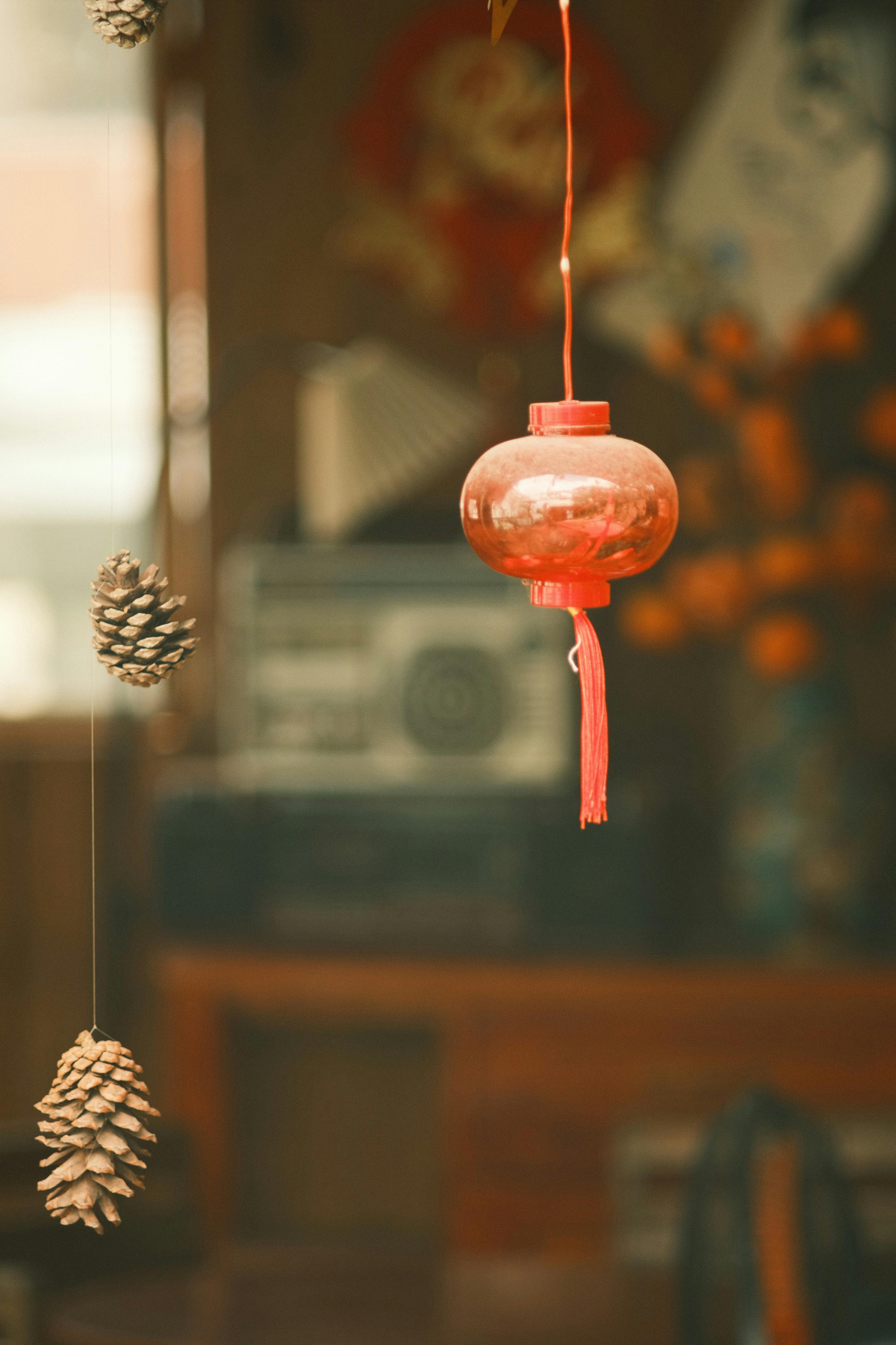 grátis Cena interna aconchegante com uma lanterna vermelha, pinhas penduradas e decoração retrô, evocando uma atmosfera calorosa e festiva. Foto profissional