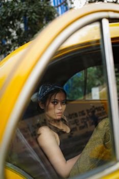 Young woman in a yellow taxi gazing outside, captured in a candid moment.