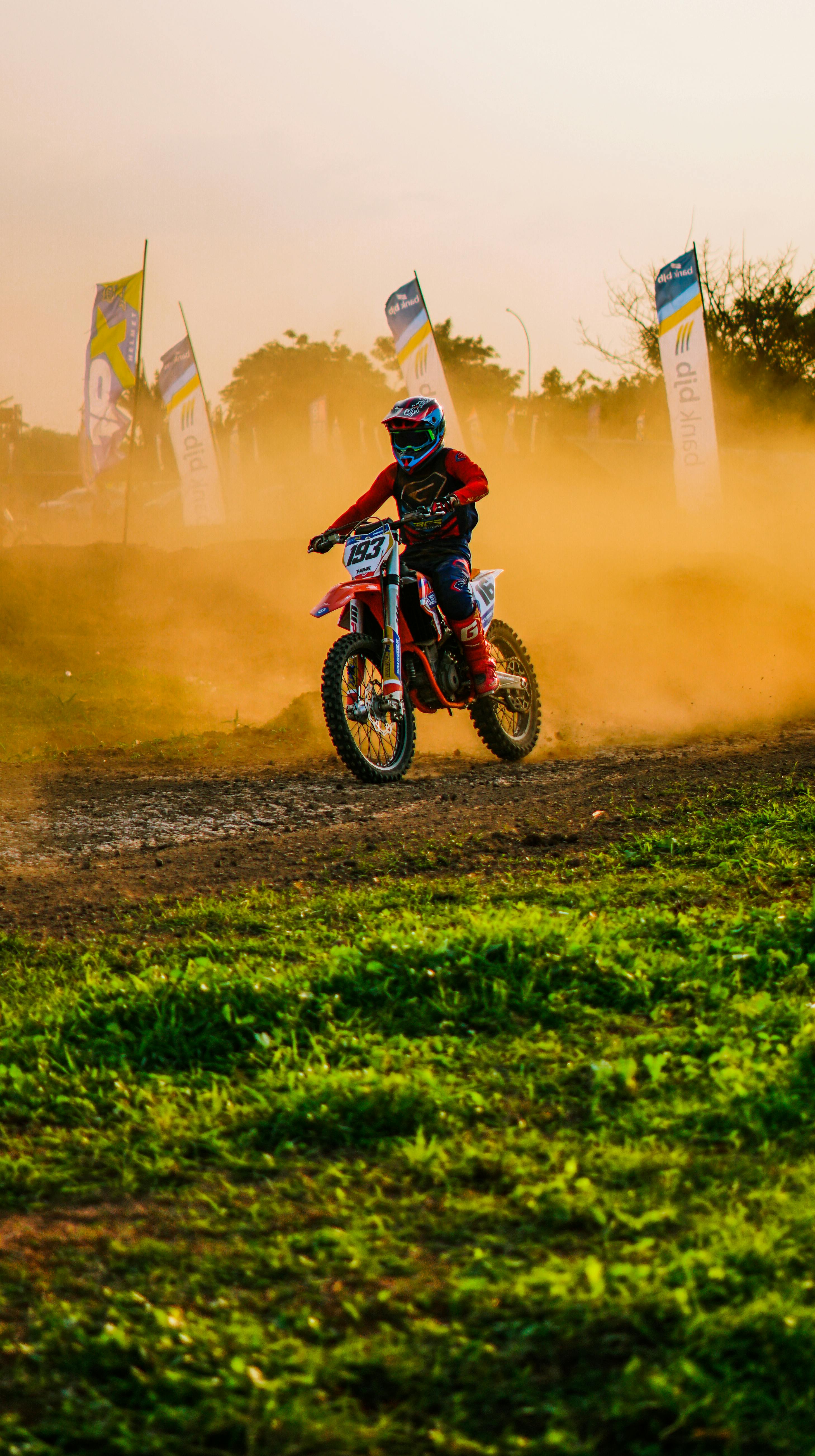 A vibrant motocross action shot during dusk in Jakarta, showcasing skilled off-road biking maneuvers.