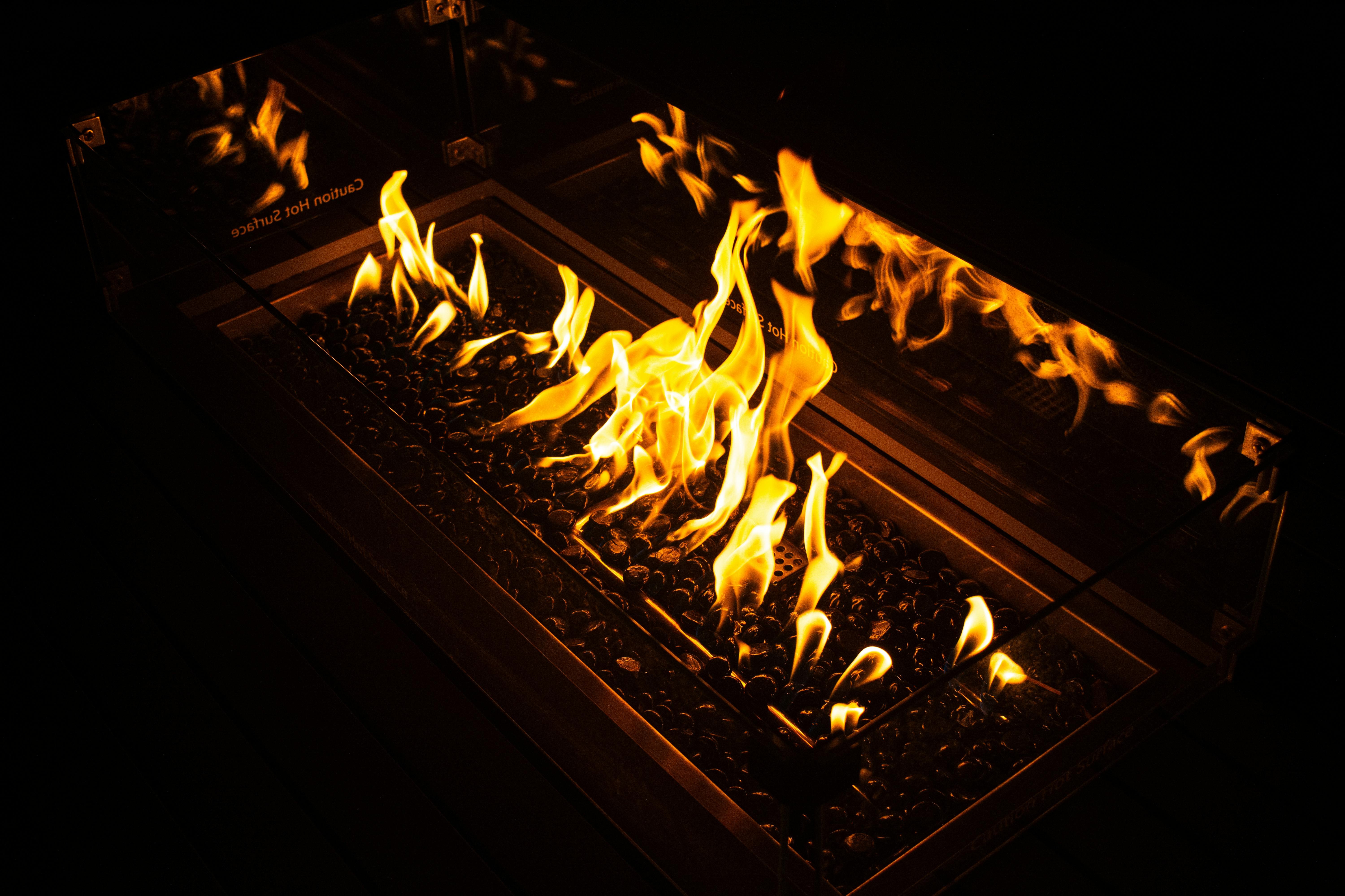 Kostenlos Eine bezaubernde Feuerstelle mit tanzenden Flammen und glühenden Kohlen vor dunklem Hintergrund. Ideal für eine gemütliche Atmosphäre. Stock-Foto