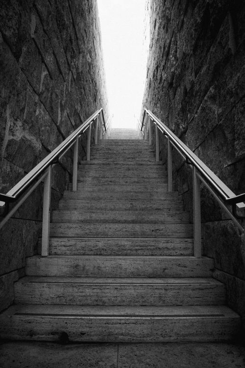 Free Black and white image of a stone staircase ascending into bright light. Stock Photo