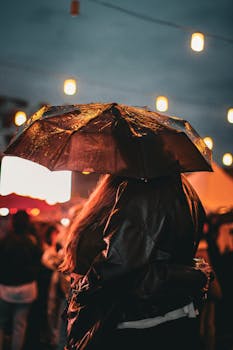 Captivating moment of a live concert in Ankara, captured during a rainy night with vibrant lights and umbrellas.