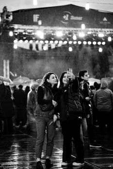 Adults taking a selfie at an outdoor concert in rainy Ankara, capturing the lively atmosphere.