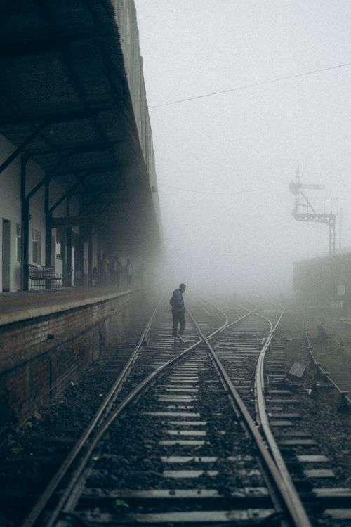 Free A lone traveler walking on fog-covered railway tracks at a Sri Lankan train station. Stock Photo