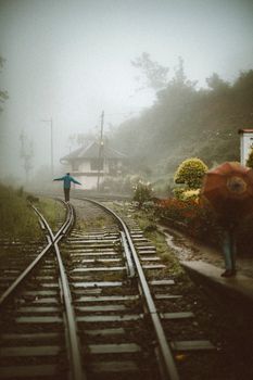 A person walking along foggy train tracks in scenic Sri Lanka, embodying a sense of adventure.