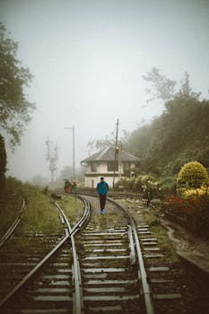 A person walking on foggy train tracks in lush greenery, Sri Lanka.