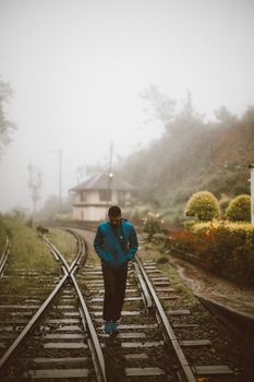 A solitary figure walks along foggy train tracks in Sri Lanka, capturing the essence of travel and exploration.
