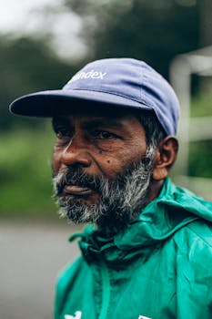 Thoughtful bearded man in a blue cap and green jacket, captured outdoors in Sri Lanka.