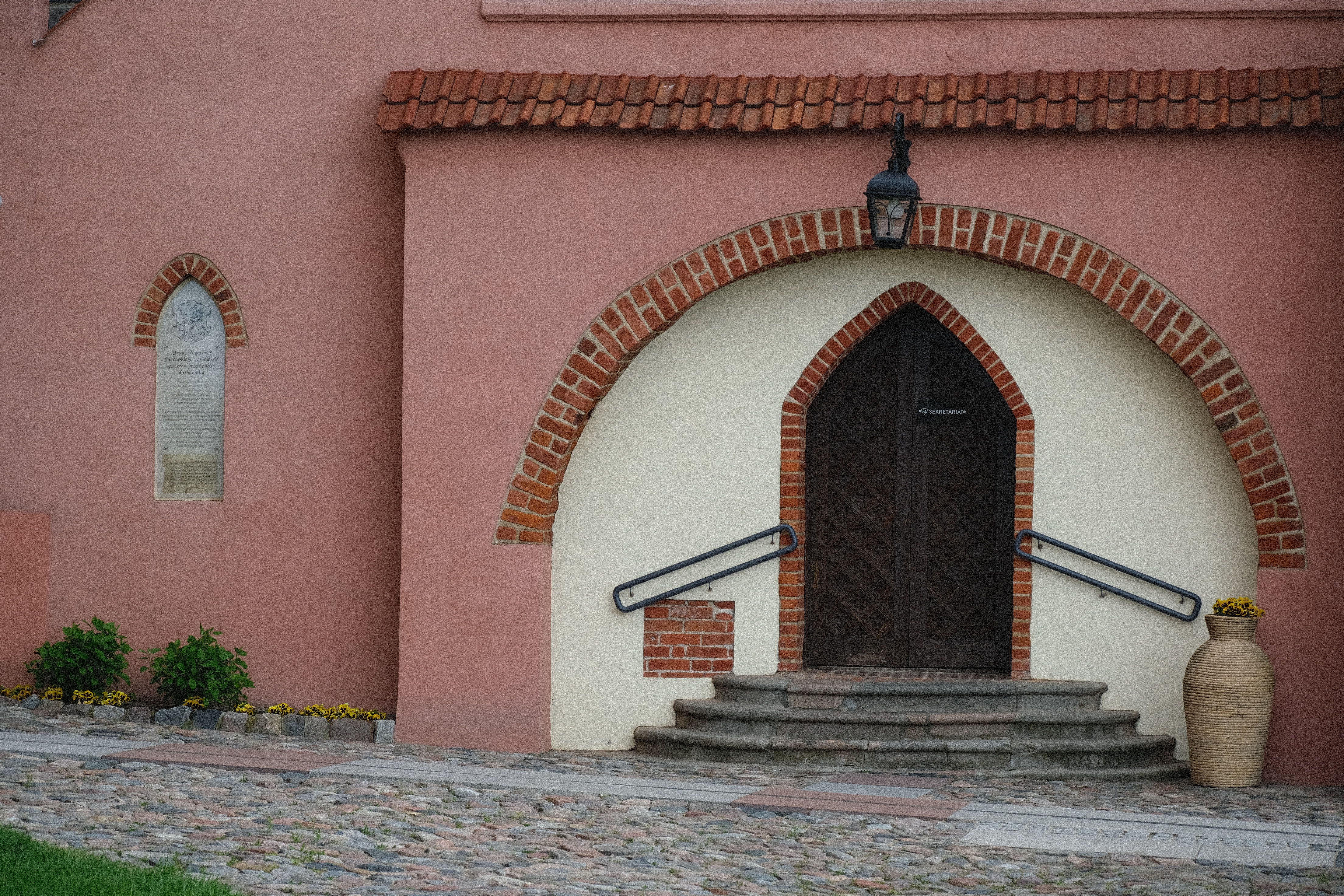 Charming entrance with brick arch and steps leading to a wooden door on a historic building.